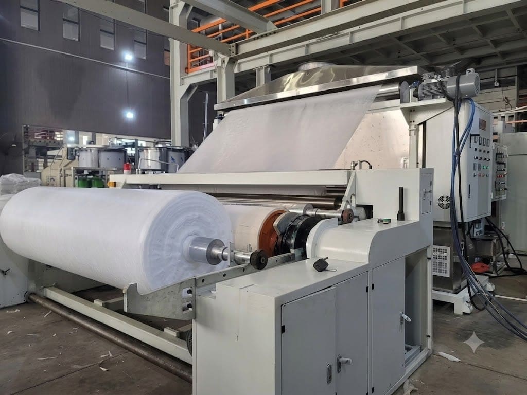 Máquina de producción de textiles no tejidos con rollo de material blanco en la planta de FILTERTEX